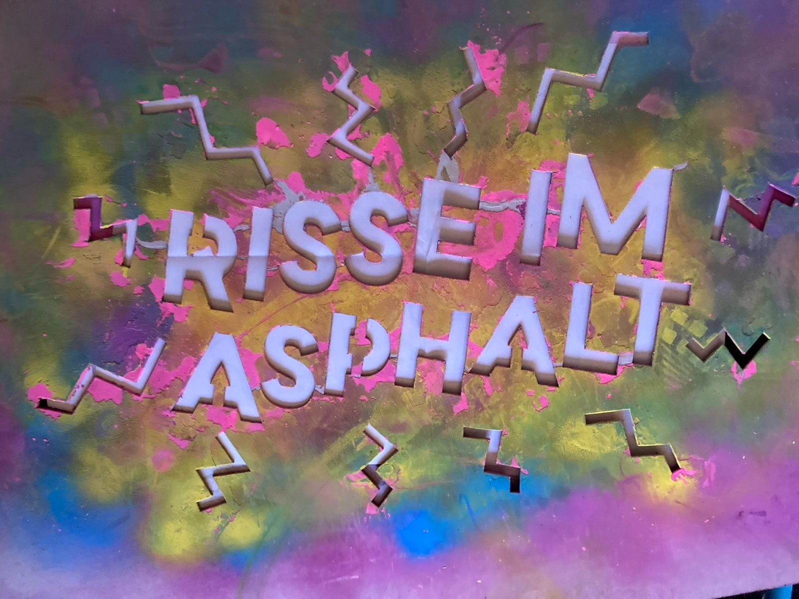 Risse im Asphalt Schriftzug Sprühkreide